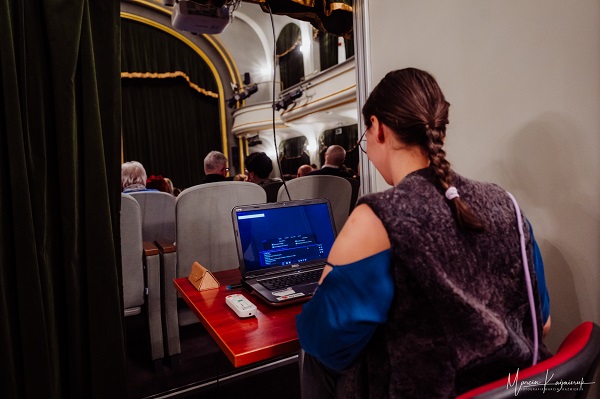 Na zdjęciu widzimy stanowisko wyświetlania napisów. Przy laptopie, na którym przygotowane jest oprogramowanie, siedzi pracownica Teatru.