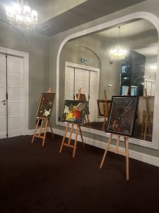 Obrazy na sztalugach we foyer teatru.