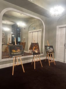 Obrazy na sztalugach we foyer teatru.