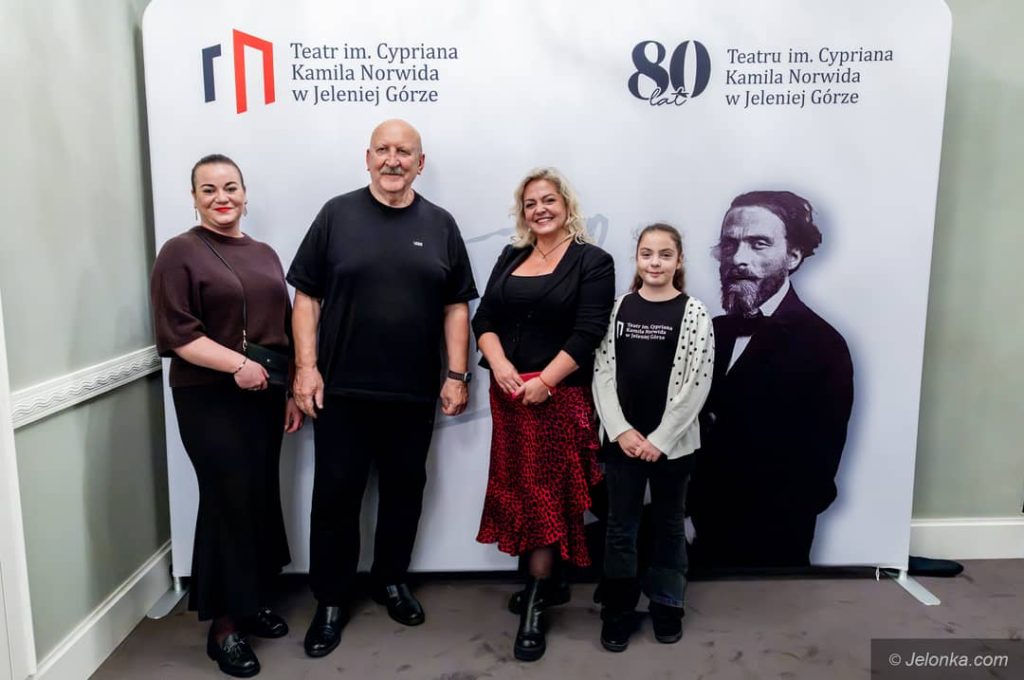 Grupka osób pozująca do zdjęcia na tle ścianki fotograficznej.