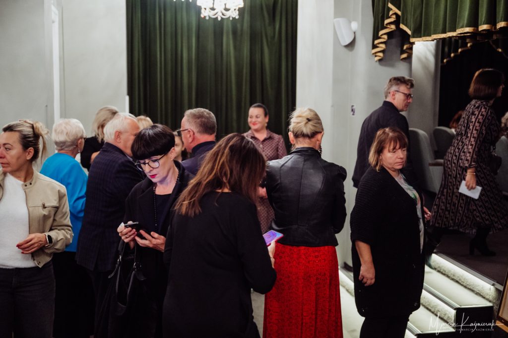 Grupa osób stojąca przed wejściem do sali teatralnej.