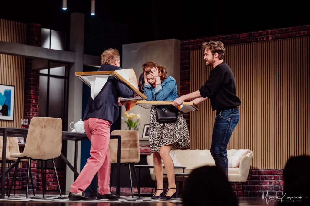 Trzy osoby biegają w ramach od rozbitych na nich obrazów.